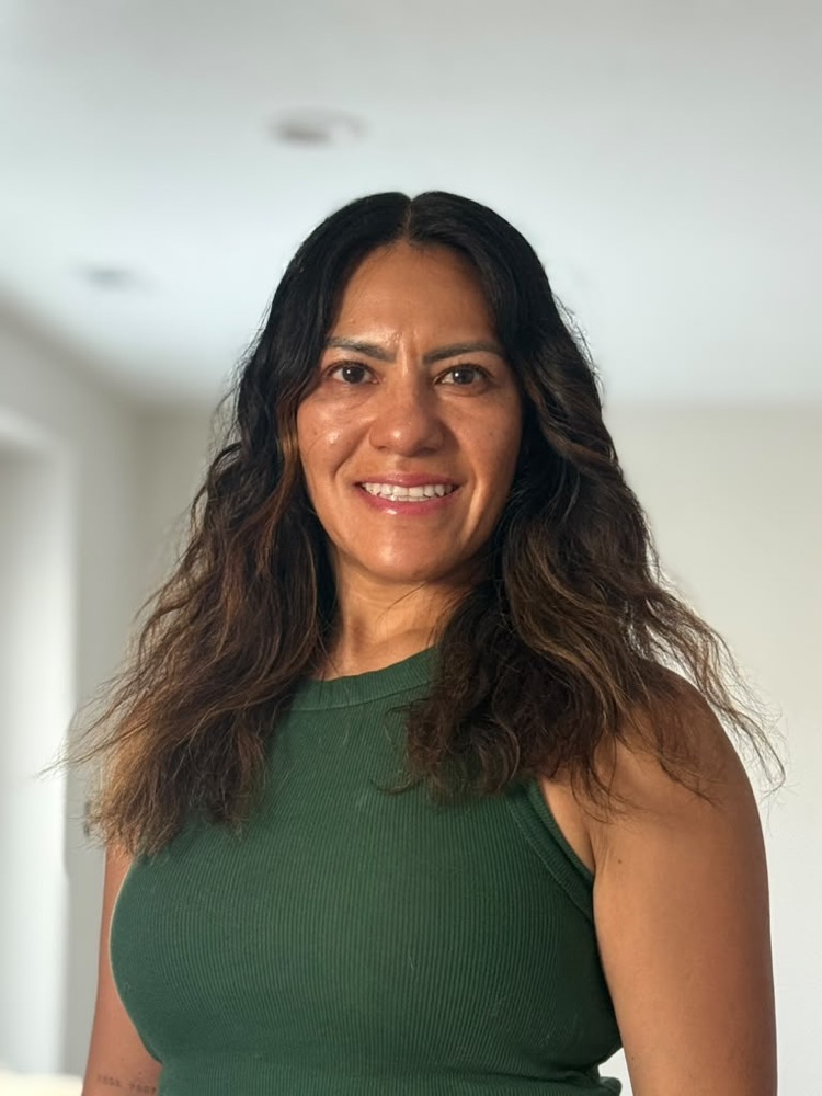 Sue Whetten smiling, with loose hair and a green top